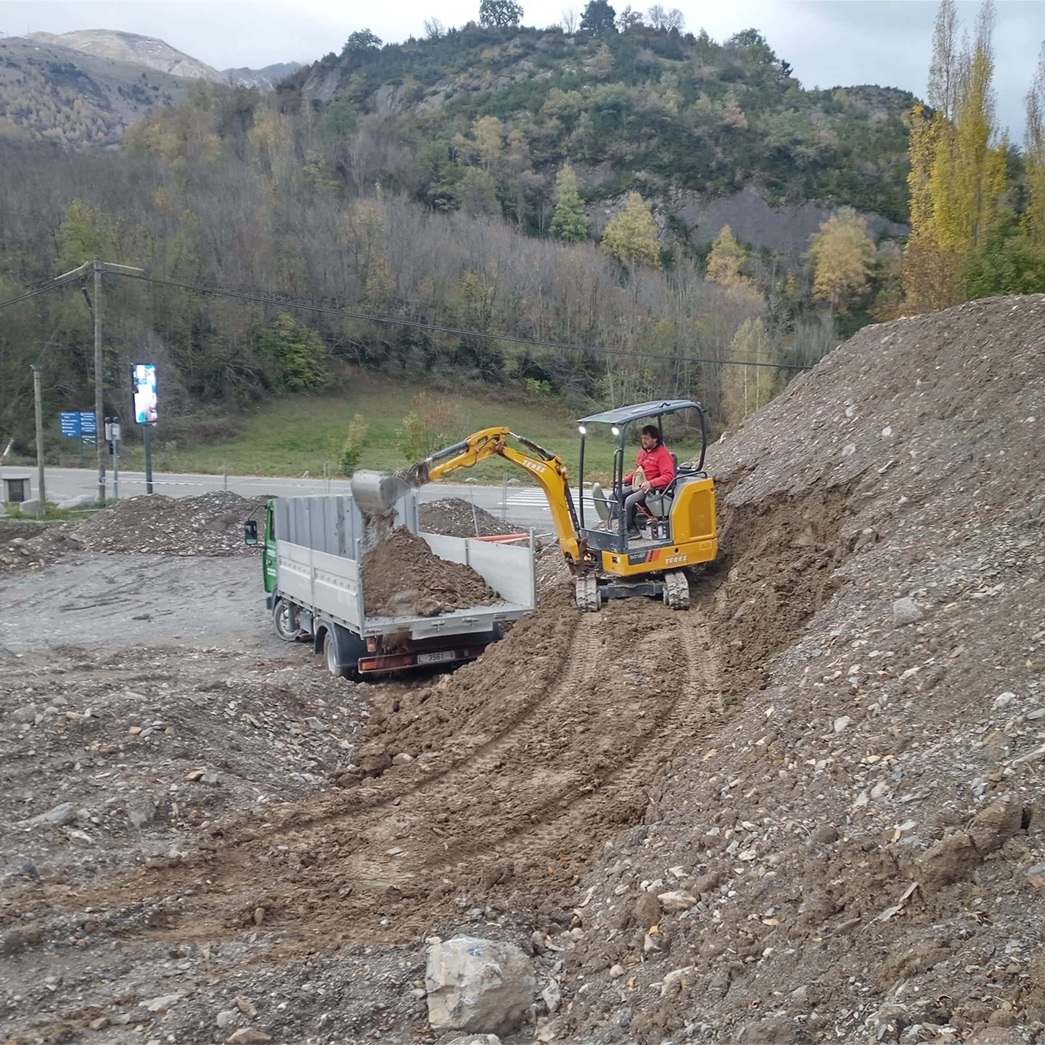 Maquinaria de excavación y movimiento de tierra en trabajo de obras públicas. Excavadora cargando tierra en camión, servicios de excavación y nivelación en proyectos de construcción en terrenos rurales.