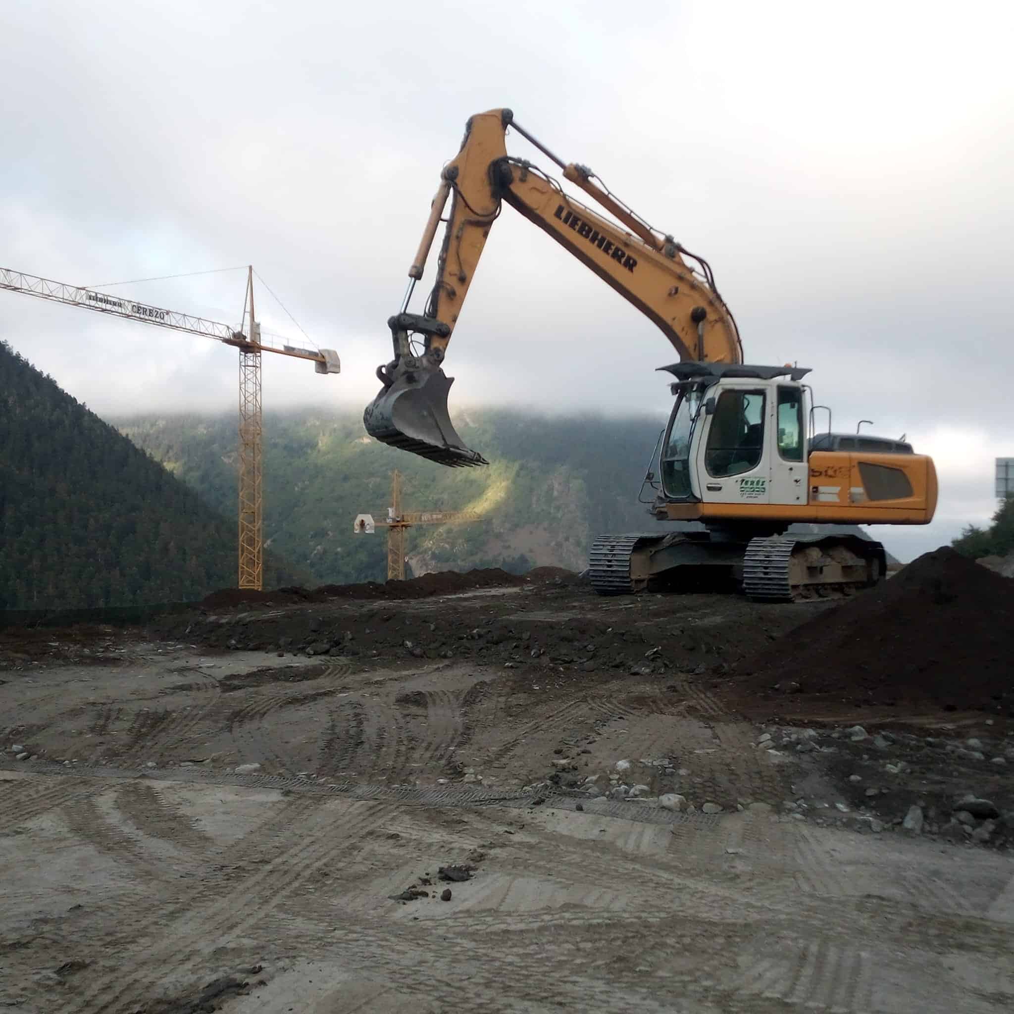 Maquinaria de excavación en obra de construcción, excavadora Liebherr en movimiento en terreno de tierra y rocas, servicios de obras y construcción Terés, trabajos especializados en obras públicas y privadas.