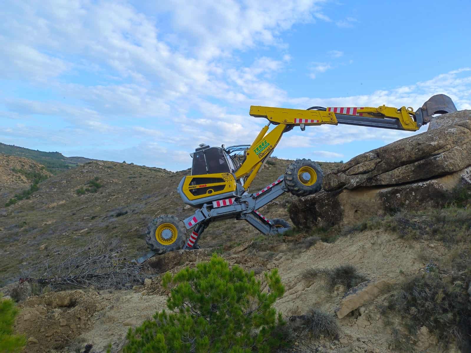 Maquinaria de construcción realizando trabajo en terrenos irregulares, especializado en trabajos de excavación y movimiento de tierra en áreas rurales y montañosas.