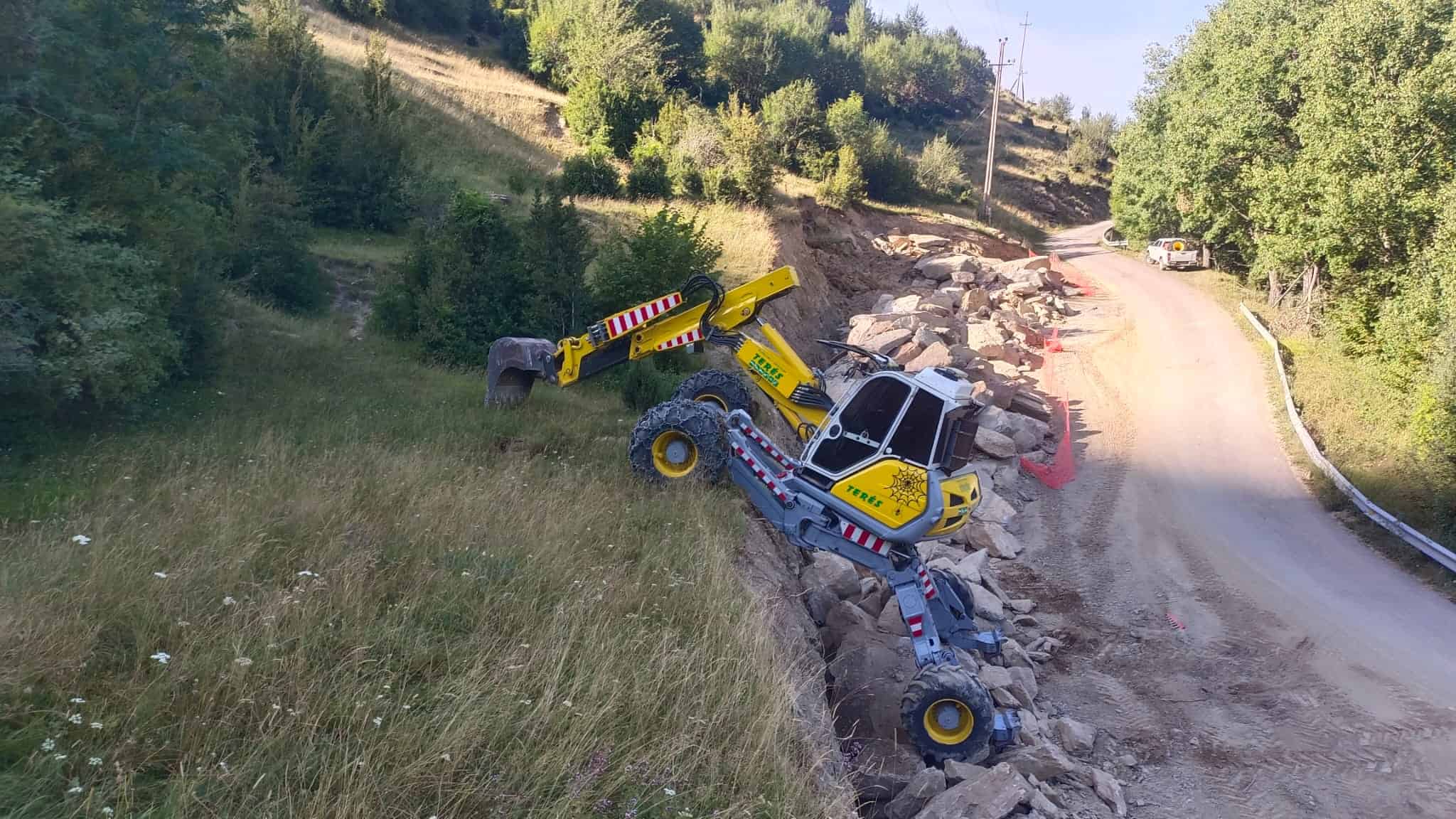 Maquinaria de obra en proceso de estabilización de talud en carretera rural.