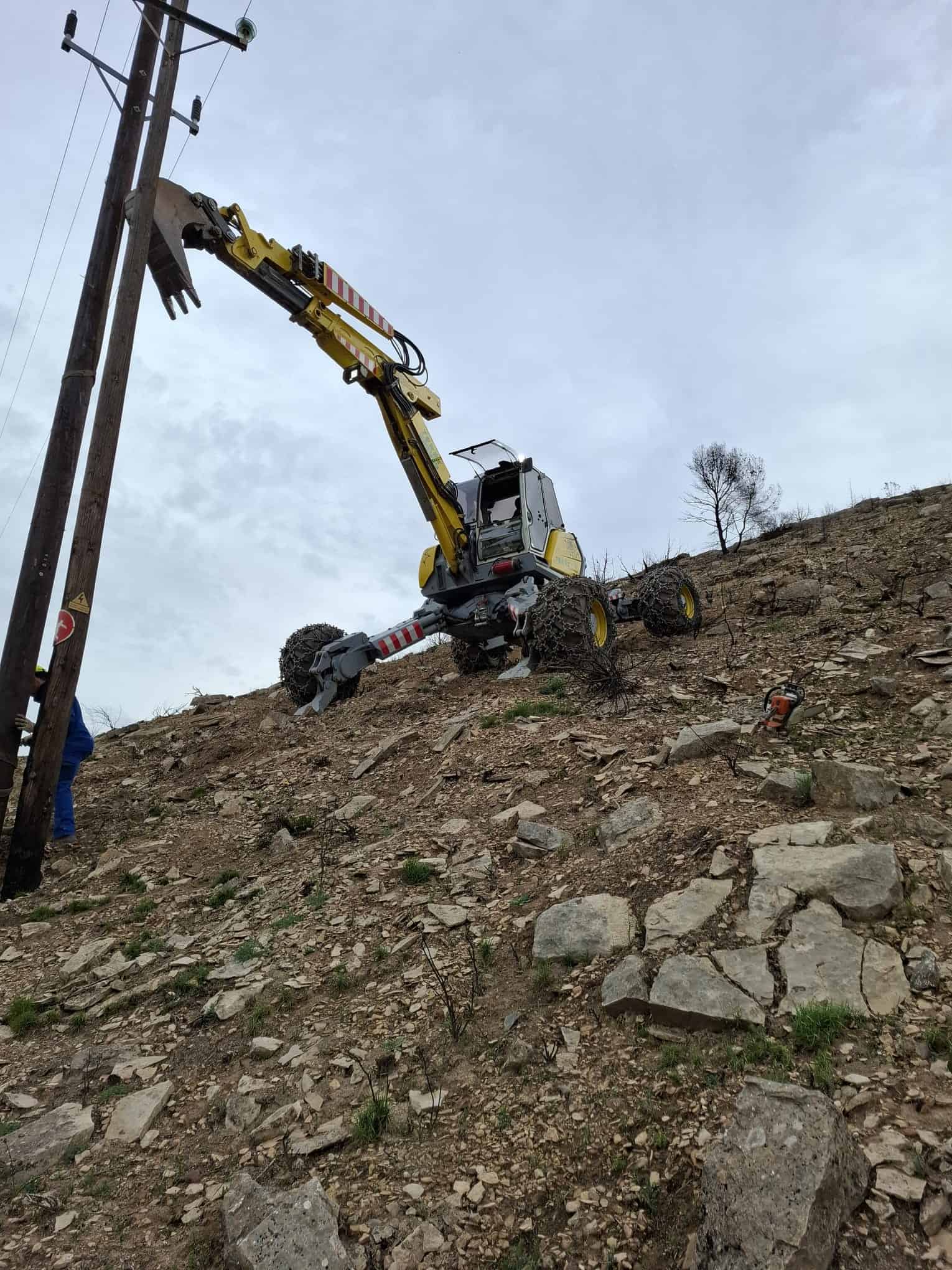 Excavadora trabajando en la retirada de rocas y tierra en un terreno montañoso. Servicios de construcción, movimiento de tierras y trabajos en terrenos difíciles en Trabajos y Servicios Terés.