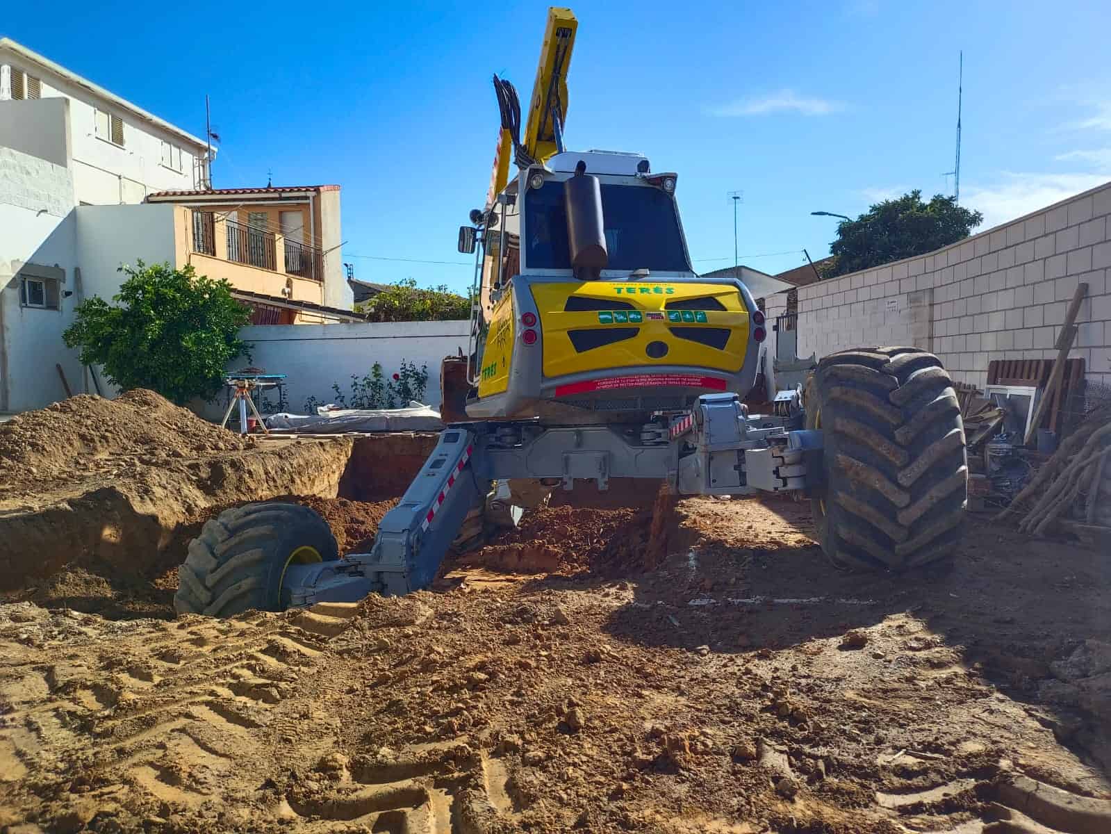 Excavadora trabajando en proyecto de construcción en zona residencial, servicios de obras civiles y movimiento de tierra por Trabajos y Servicios Terés.