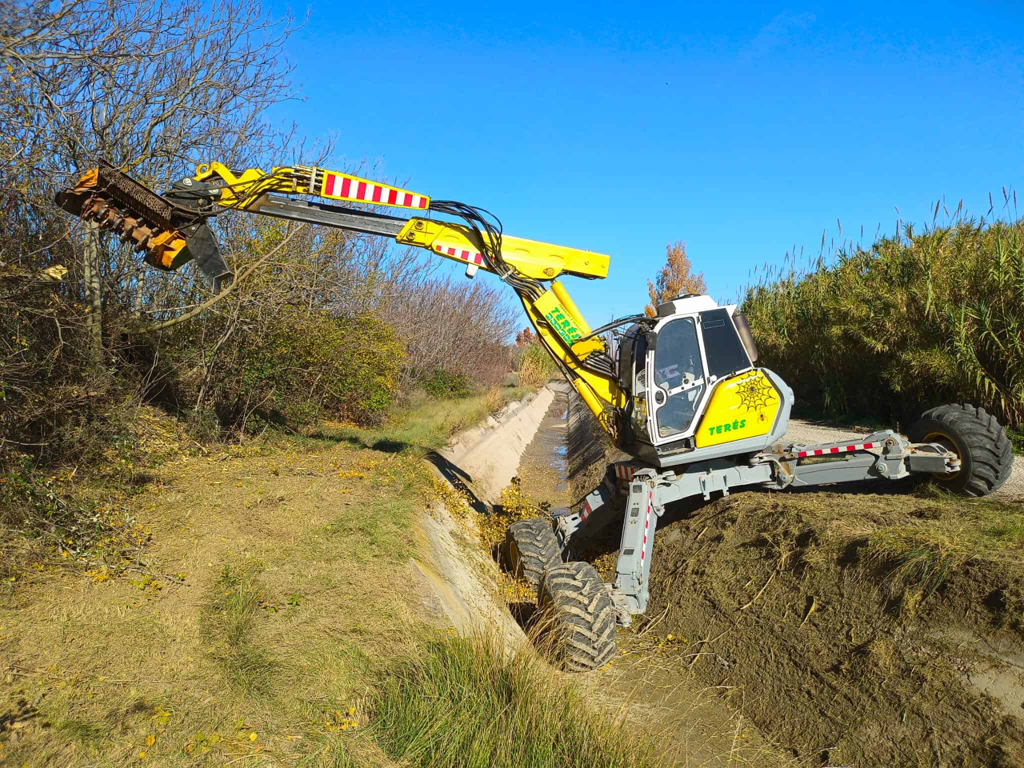 Maquinaria agrícola y trabajos en zanjas. Excavadora trabajando en campo rural. Servicios de excavación y mantenimiento de terrenos con maquinaria especializada en Terés.