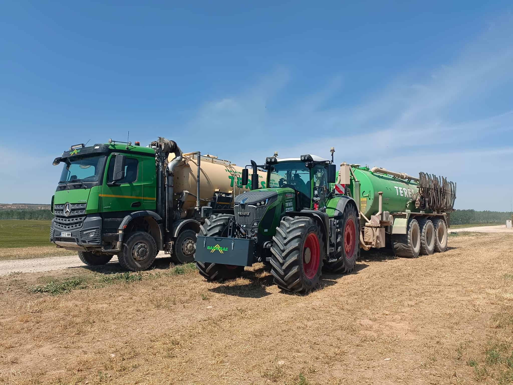 Vehículos agrícolas y camiones de transporte de agua en campo rural para trabajos de agricultura y servicios de extracción de agua, con maquinaria moderna y eficiente.