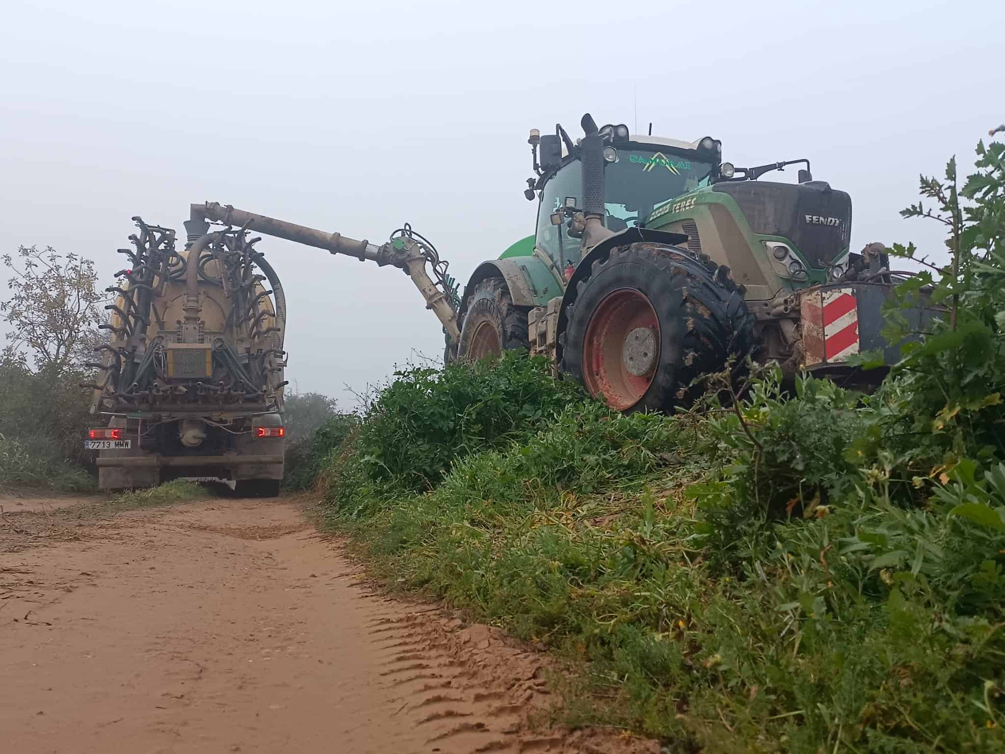 Camión con maquinaria agrícola realizando trabajos de limpieza y mantenimiento en el campo.