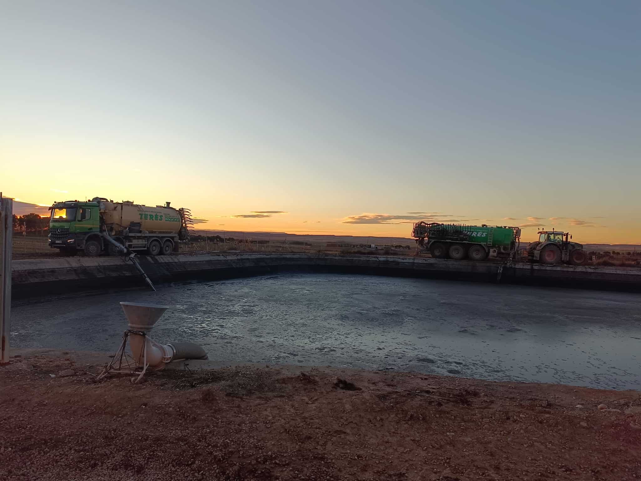 Aro de fertilización con camiones aspersores realizando trabajos en obras rurales, en un atardecer con cielo despejado y horizonte abierto, en la provincia de Terés.